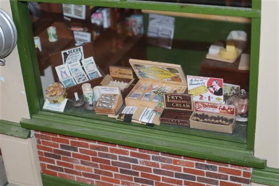 A group of three dolls house models of shops with figures and accessories and an unfinished dolls house